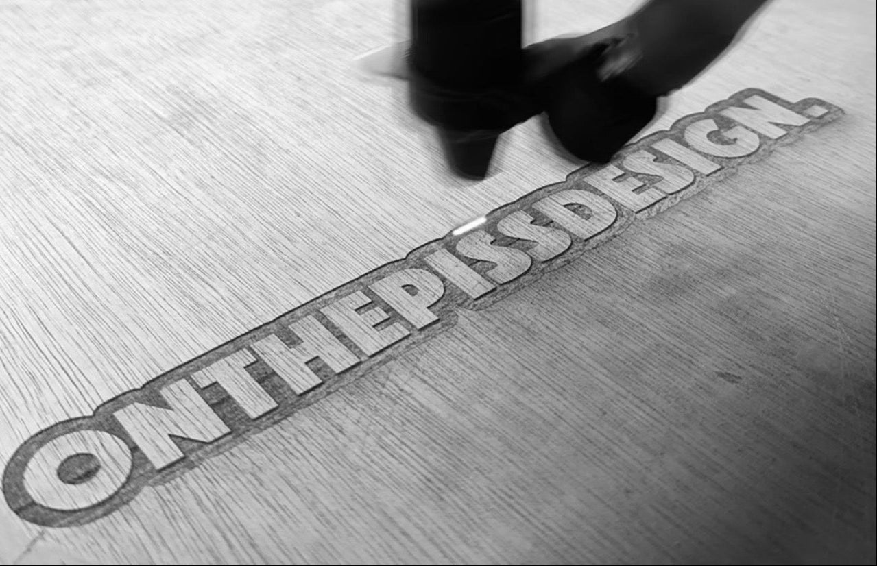 Metallic 'ON THE PISS DESIGN' logo on a textured surface